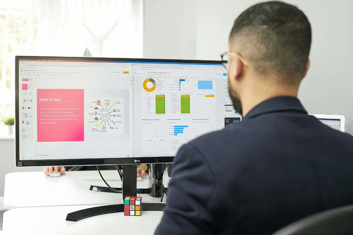 SEO professional reviewing analytics dashboards and SEO strategy documents on dual monitors.